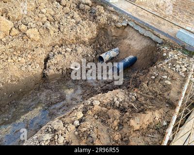 An excavated pit is a ditch for laying cables and wires with pipes under the ground during the construction and repair of houses in the city of the me Stock Photo