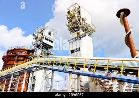 Metal iron structures, industrial production with a conveyor, a drill for ore mining, pipes, railings and pipelines at the production of an oil refini Stock Photo