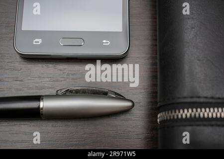 phone with a pen and purse lie on a wooden table background Stock Photo