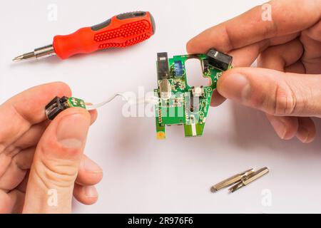 board in hands on a white background with a red screwdriver and interchangeable tips with a screwdriver Stock Photo
