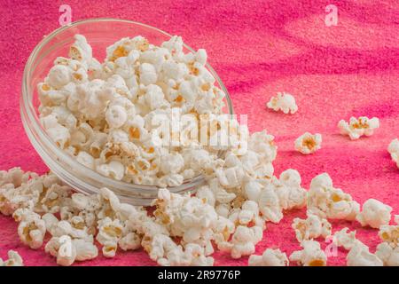 popcorn in a glass plate, on a pink uneven background Stock Photo