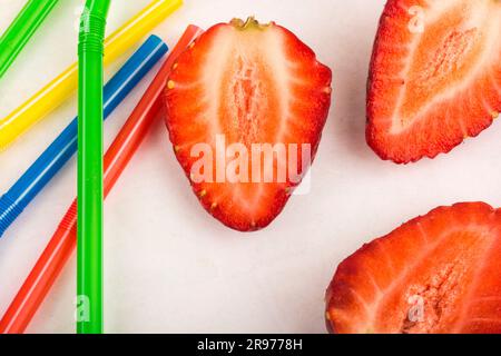 Strawberry and colored straws scattered on a white background Stock Photo