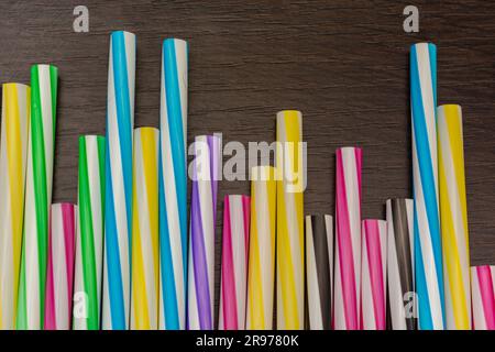 Colorful paper straws on a wooden background. Accessories for events and parties. multicolored background Stock Photo