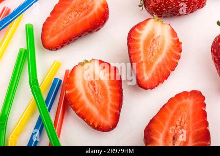 Strawberry and colored straws scattered on a white background Stock Photo