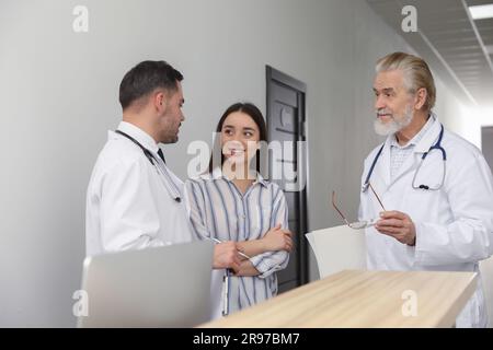 Doctors consulting patient near reception desk in clinic hall Stock Photo