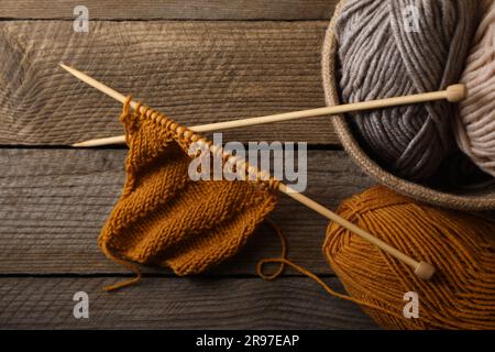 Soft colorful yarns, knitting and needles on wooden table, top view Stock Photo