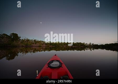 Red kayak on Coot Bay in Everglades National Park, Florida with moon in background during evening twilight. Stock Photo