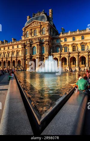 FRANCE. PARIS (75) 1ST DISTRICT. LOUVRE MUSEUM. TOURISTS REFRESHING IN A BASIN AT THE COUR NAPOLEON Stock Photo