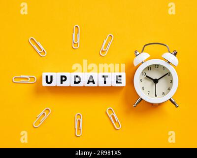The word update on cubes with alarm clock and paper clips. Time for a software update. News update announcement. Stock Photo