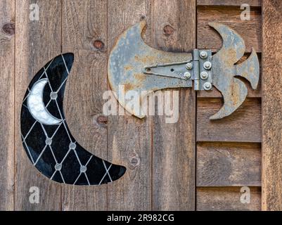 A gothic metal hinge and crescent moon design on an old wooden door Stock Photo