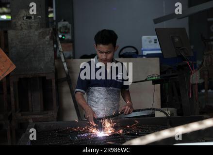 Jakarta, Indonesia - June 20, 2023 : A worker cuts iron plates with a shearing machine Stock Photo