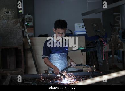 Jakarta, Indonesia - June 20, 2023 : A worker cuts iron plates with a shearing machine Stock Photo
