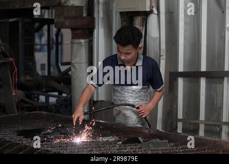 Jakarta, Indonesia - June 20, 2023 : A worker cuts iron plates with a shearing machine Stock Photo