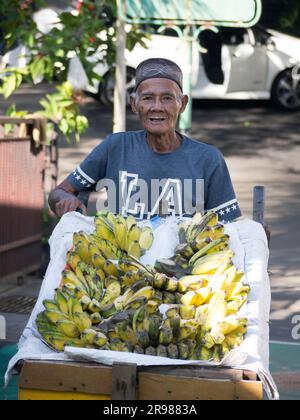 Jakarta, Indonesia - June 20, 2023 : portriat asian senior man traveling banana seller by cart smiling looking at the camera Stock Photo