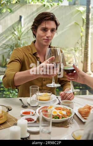Young man looking at girlfriend when toasting with wine glass Stock Photo