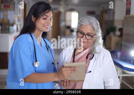 Doctors discussing patient case status with his medical staff after operation. Pharmaceutical representative showing medical report. Stock Photo
