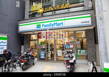 Kyoto Japan, Family Mart convenience store mini supermarket in downtown Kyoto, cyclist outside and parked scooters,Japan,Asia,2023 Stock Photo