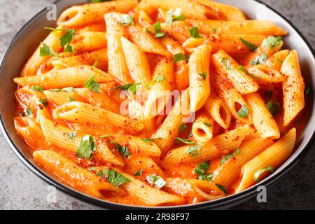 Penne pasta with pink sauce from tomatoes, cream and mozzarella cheese close-up in a bowl on the table. horizontal Stock Photo