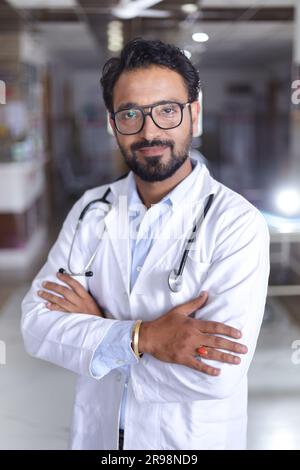 Happy Indian senior Medical professional standing portrait in hallway of hospital dressed in scrubs and lab coats, with stethoscopes. Stock Photo