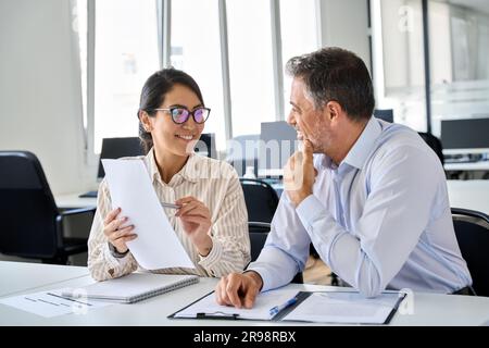 Two happy diverse managers working in office discussing financial documents. Stock Photo