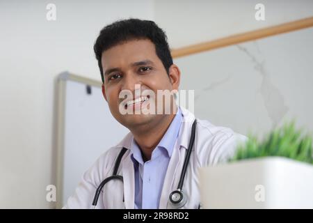 young Indian doctor sitting with patient having a detailed conversation. Happy young doctor smiling. Consultation service concepts. Stethoscope. Stock Photo