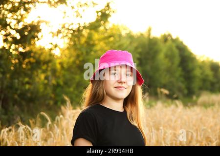 A cheerful teenage girl, aged 12 or 13, stands gracefully in a vibrant yellow summer background. Her radiant smile complements as she enjoying Stock Photo