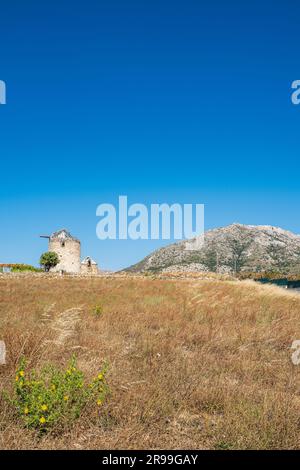 Derelict traditional Greek windmill set in the hay making countryside of Naxos, Greece Stock Photo