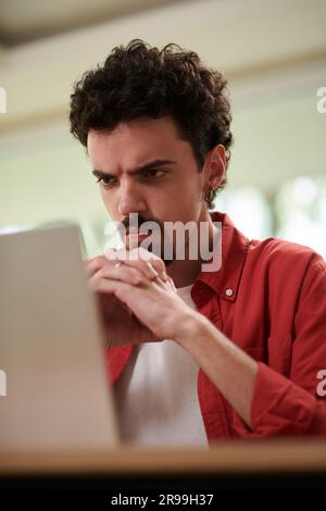 Frowning man looking at laptop screen with programming code Stock Photo