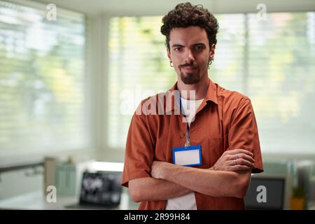 Portrait of smiling confident developer standing in office with arms crossed and looking at camera Stock Photo