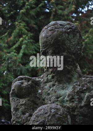 Closeup photo of destroyed statue showing all its imperfections. The contrast between beauty of the nature in the background and the damaged stone. Stock Photo