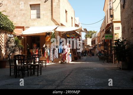 View of a narrow alley with small stores and taverns in the old town of Rhodes on the island of Rhodes in Greece Stock Photo