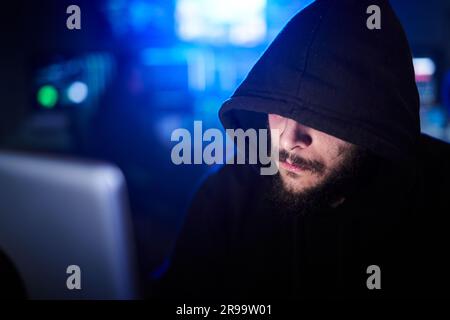 Close up hidden hacker in sweatshirt and hoodie hacking security systems. Cyber attack and malware. Stock Photo