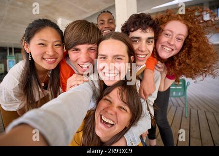Smiling group multi-ethnic students posing for selfie mobile phone gathered on college campus.  Stock Photo