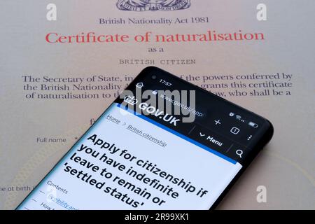 Smartphone with Citizenship online application page placed on top of Certificate of naturalisation as a British Citizen. Stafford, United Kingdom, Jun Stock Photo