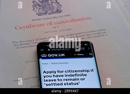 Smartphone with Citizenship online application page placed on top of Certificate of naturalisation as a British Citizen. Stafford, United Kingdom, Jun Stock Photo