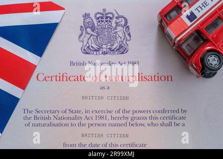 UK flag and double decker bus placed on top of authentic Citizenship certificate. Certificate of naturalisation as a British Citizen. Stafford, United Stock Photo