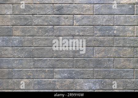 Textured background of rectangular dark stone tiles with scuffs, laid in even rows. Close-up. Stock Photo