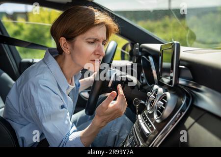 Bad smell from ac inside car. Woman driver feels an unpleasant odor after turn on air conditioning Stock Photo