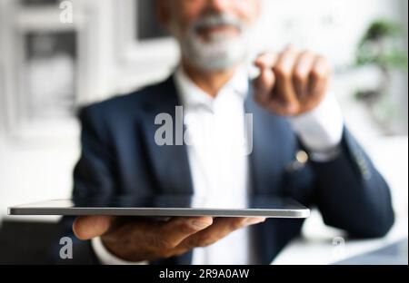Serious handsome mature european man with beard in suit works, use tablet in office interior, close up Stock Photo