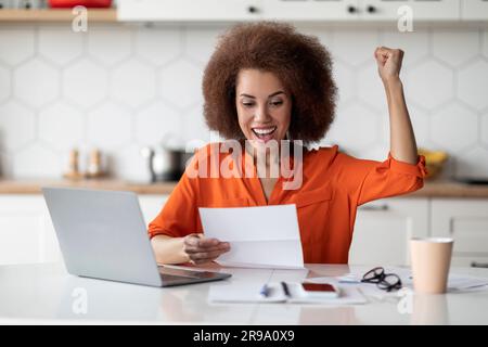 Portrait Of Overjoyed Black Happy Woman Reading Letter In Kitchen Stock Photo