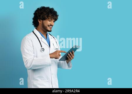 Positive young eastern doctor using digital tablet, copy space Stock Photo