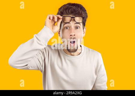 Man looking intently raising his glasses to his forehead Stock Photo