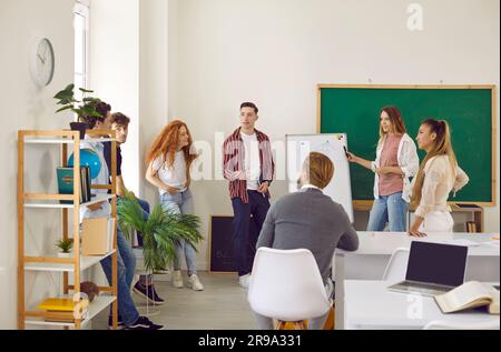 Group of college students and teacher discuss project using whiteboard during class. Stock Photo