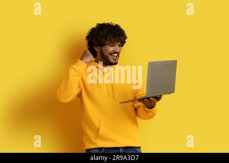 Emotional indian guy looking at laptop screen and gesturing Stock Photo
