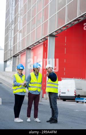 three engineers checking plans with documents outdoors Stock Photo