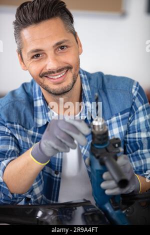 workman changing drill bit on his power tool Stock Photo