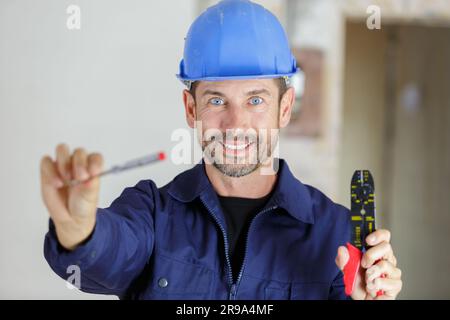 portrait of a happy young male builder showing tools Stock Photo