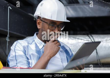electrician doing test with tablet pc in ceiling Stock Photo
