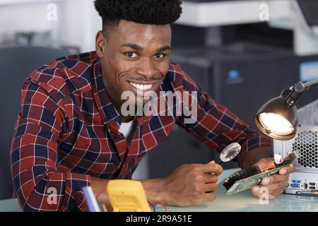 computer technician using magnifying glass and inspection lamp Stock Photo