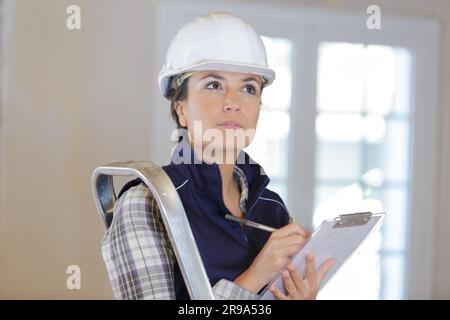female builder inspecting site and writing on clipboard Stock Photo